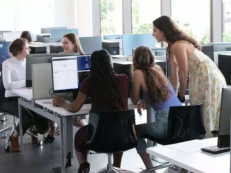 students huddled around a computer in a bright computer lab